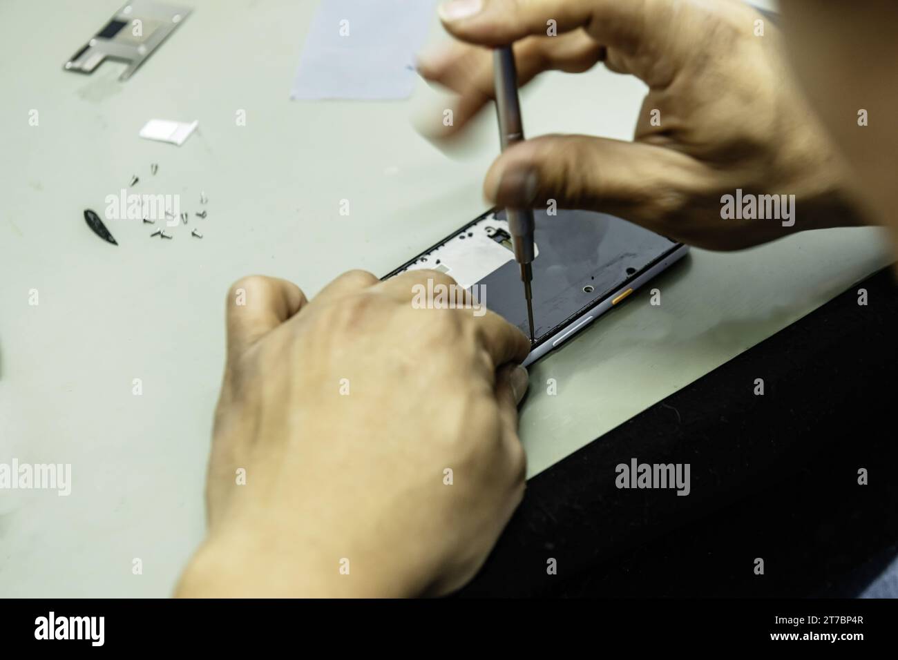 Un tecnico elettronico che smonta uno smartphone Foto Stock