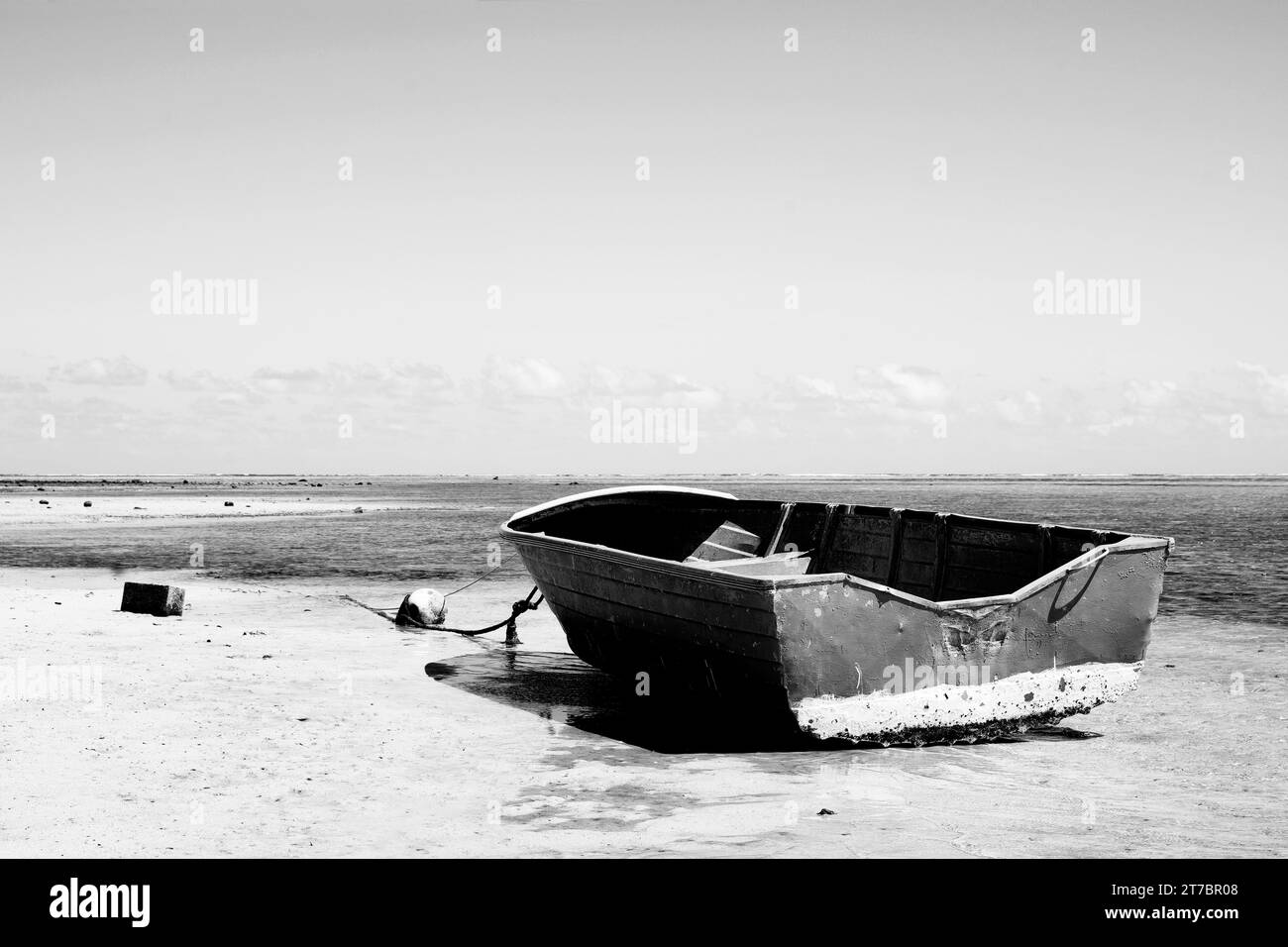 Un'immagine raffinata in bianco e nero di un'antica barca di pescatori in legno sull'asciutto durante la bassa marea nel selvaggio sud dell'isola di Mauritius. Foto Stock