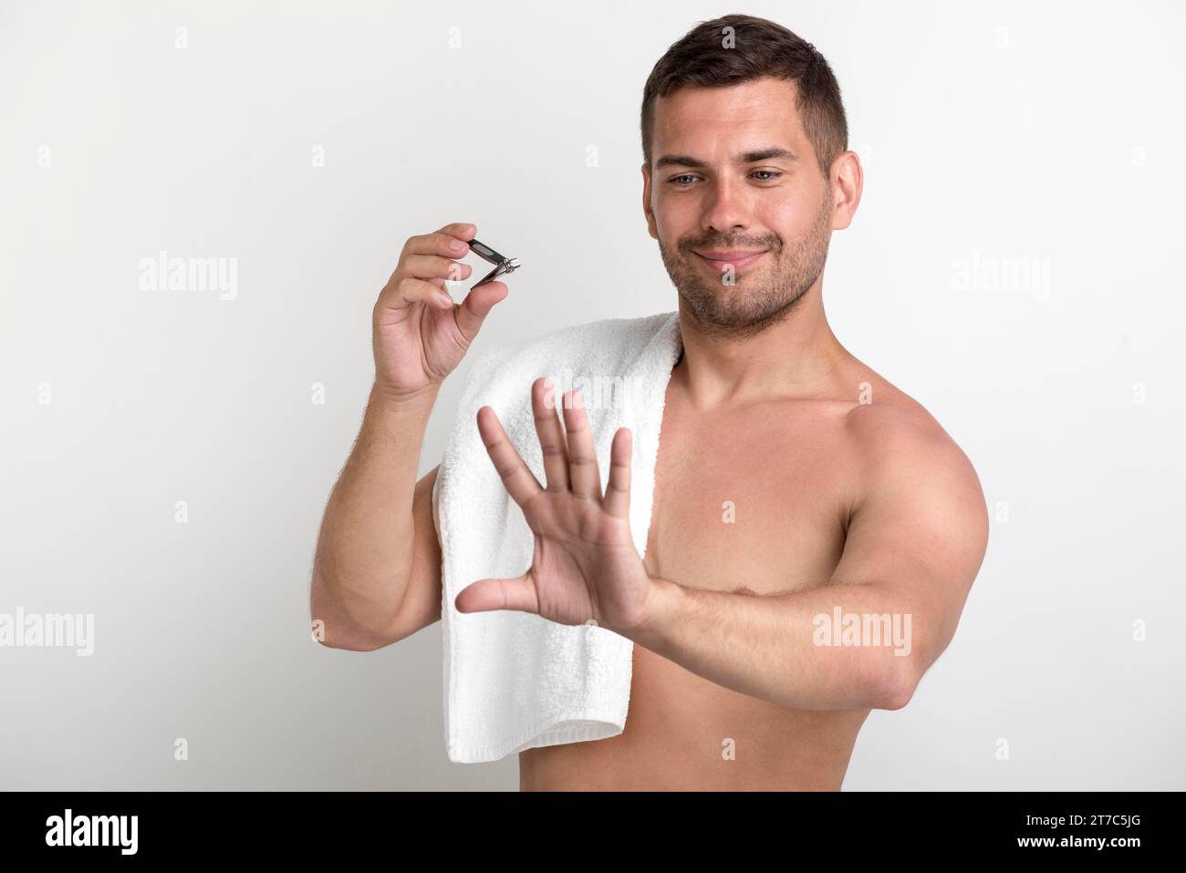 Giovane uomo sorridente che guarda la mano dopo aver tagliato le unghie Foto Stock