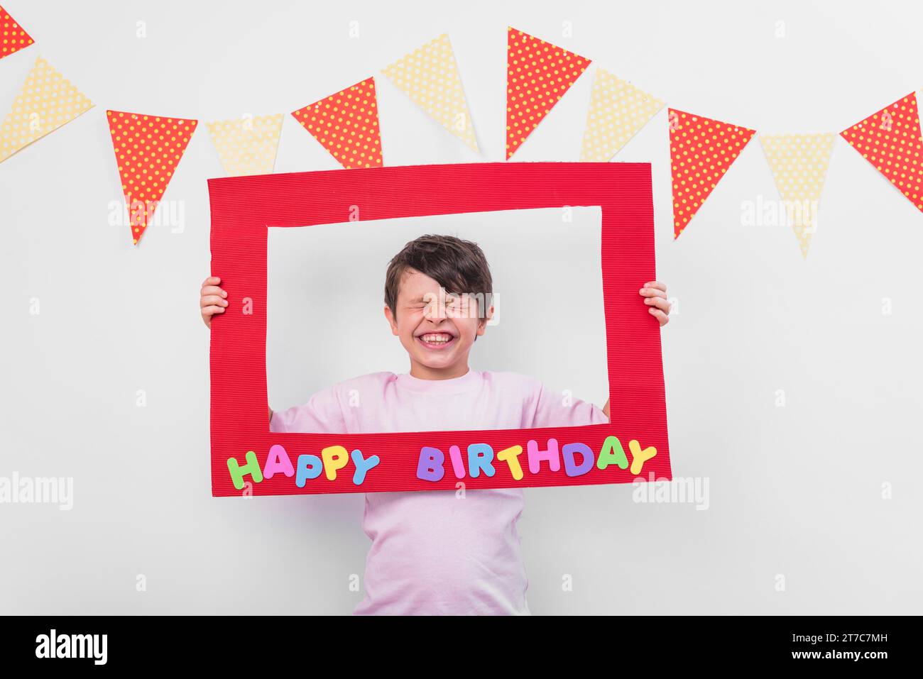 Ritratto un ragazzo carino che regge una cornice di compleanno con gli occhi chiusi Foto Stock