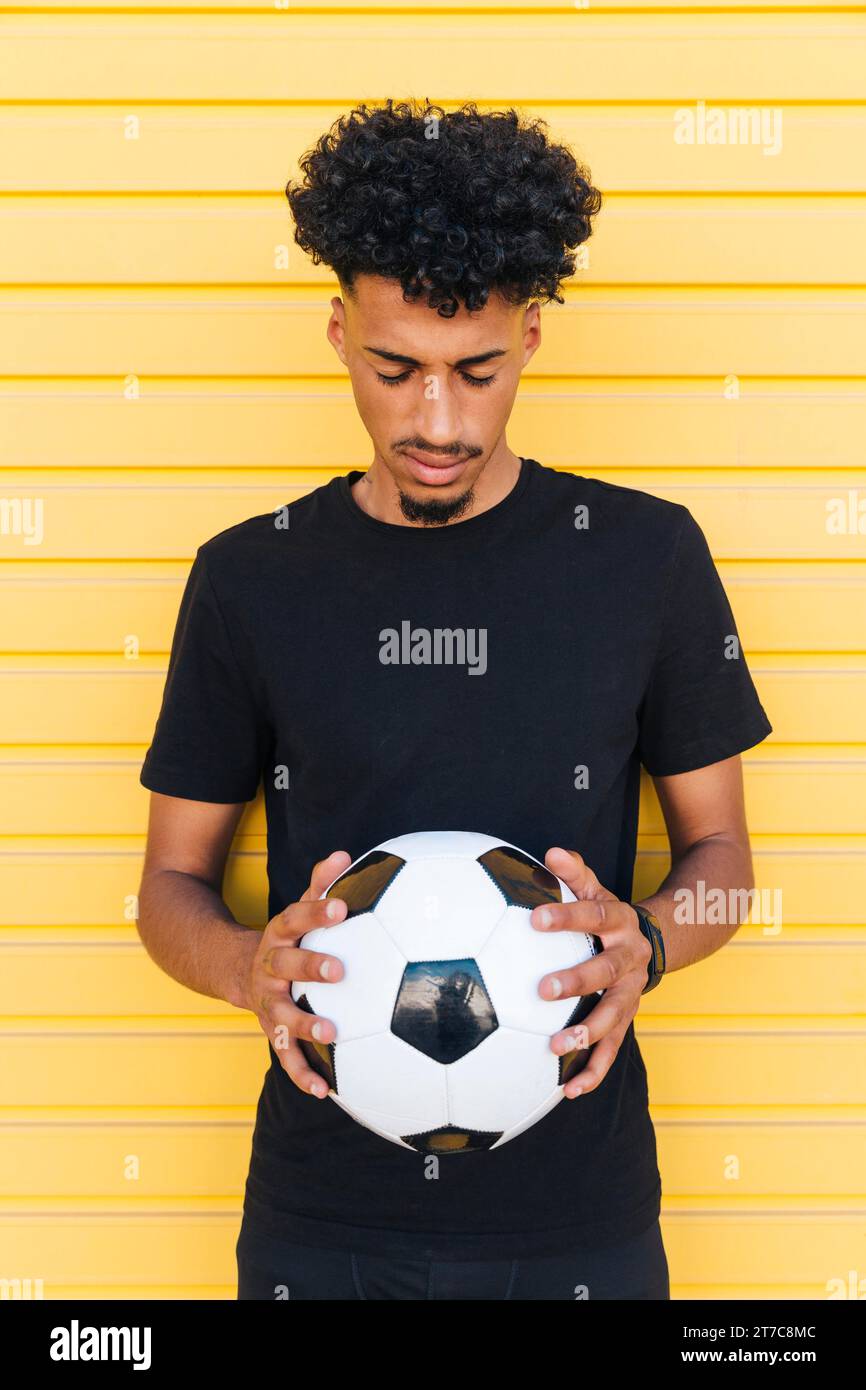 Giovane uomo nero con la palla da calcio a occhi chiusi Foto Stock