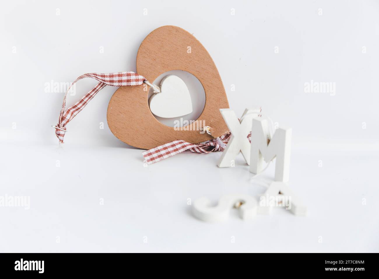 Ornamento a forma di cuore in legno con testo di Natale su sfondo bianco isolato Foto Stock