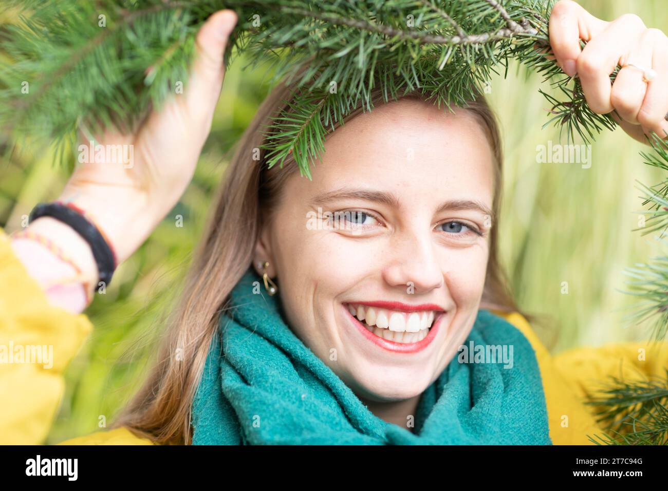 Giovane donna con un ramo verde sulla testa su un muro di una pianta come protezione ambientale Foto Stock