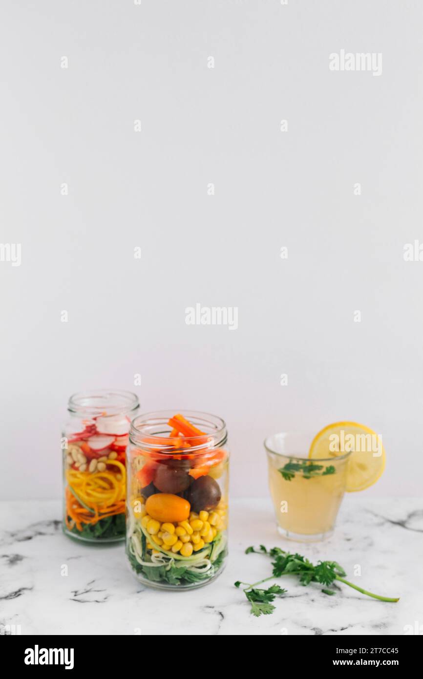 Insalata di verdure, due vasetti mason con ripiano in marmo di succo di limone in vetro Foto Stock