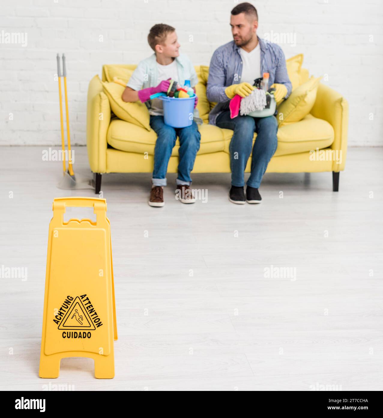 Cartello pavimento bagnato con divano uomo ragazzo Foto Stock