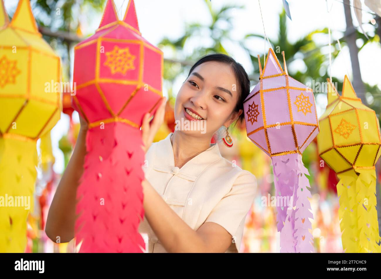 Una bella e felice donna tailandese-asiatica in abito tradizionale sta appendendo una lanterna di carta e si sta godendo il festival YI Peng o Loy Krathong in un tempio di CH Foto Stock