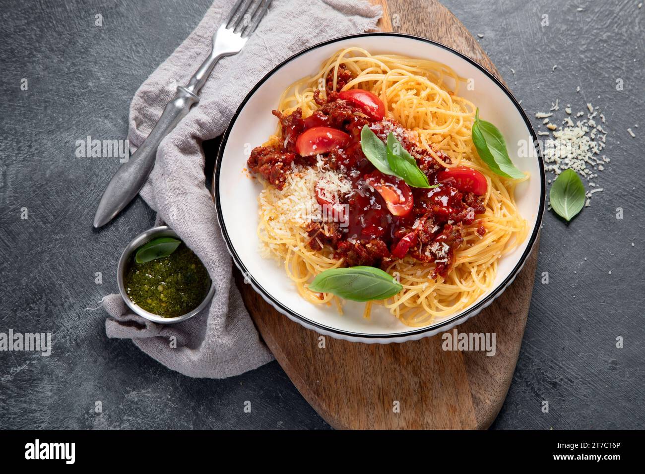 Gustosi e appetitosi spaghetti italiani classici, pasta alla bolognese con salsa di pomodoro, parmigiano di formaggio, carne e basilico su piatto su sfondo scuro. Vista dall'alto. Foto Stock