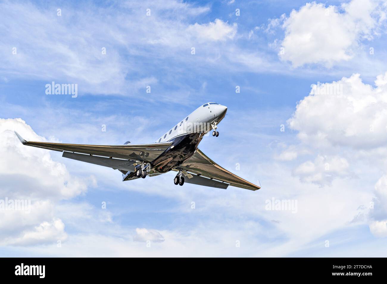 Aereo privato da lavoro che vola sotto un cielo blu con nuvole bianche Foto Stock