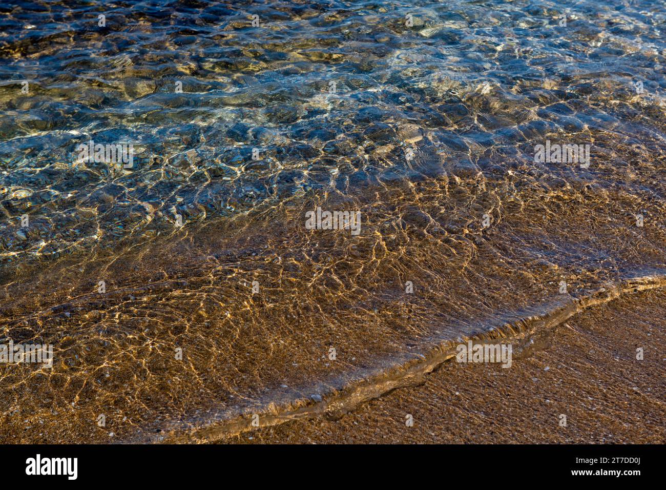 Onde gialle e acquamarine sopra i rivetti di sabbia testurizzati sulla costa mediterranea di Israele. Foto Stock