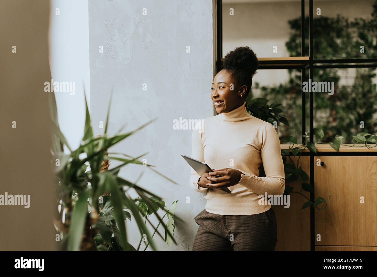Giovane donna afroamericana in piedi con un tablet digitale in ufficio Foto Stock