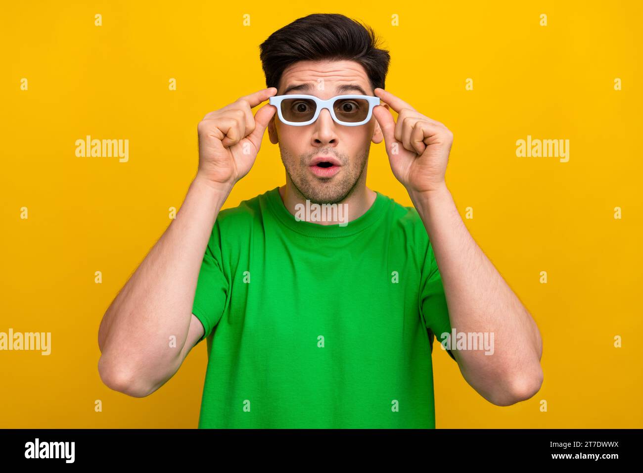 Ritratto di Guy impressionato indossa una t-shirt elegante che tocca occhiali 3d fissando gli effetti visivi moderni isolati sullo sfondo di colore giallo Foto Stock
