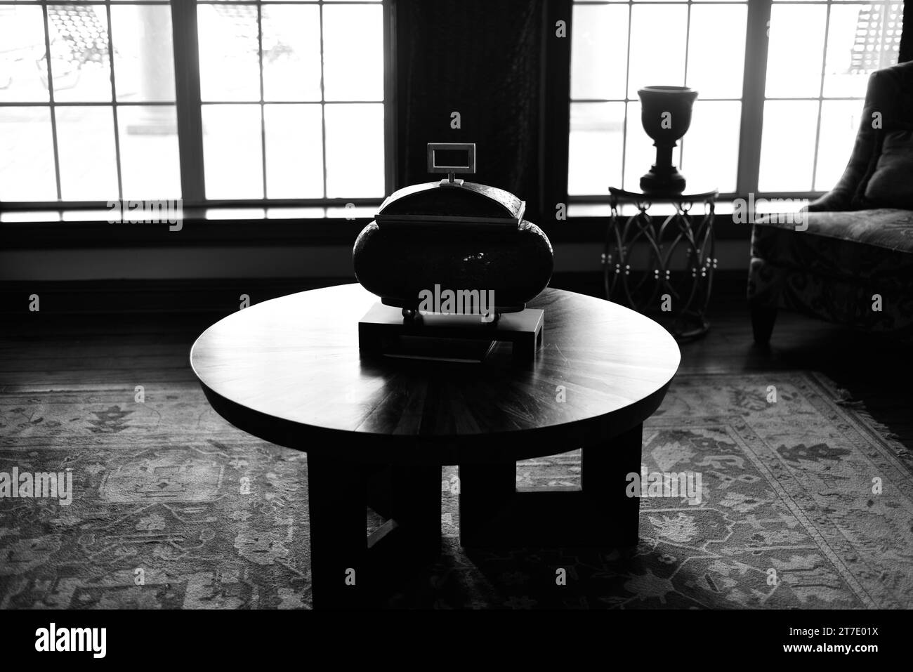 Una scena di soggiorno con un tavolino da caffè in legno e due finestre sullo sfondo Foto Stock