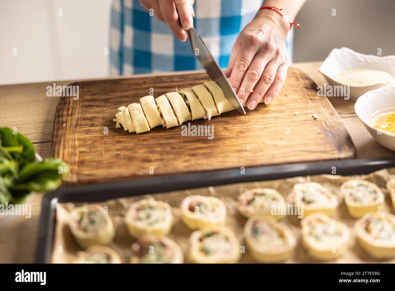 Il cuoco taglia il giro della pasta sfoglia in rotoli e lo mette sul vassoio Procedura di ricetta: 6 di 10 Foto Stock