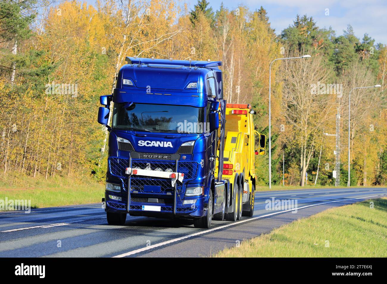 Vista posteriore di Hinaus Raasepori, un veicolo per il recupero di carichi pesanti Volvo FH che traina un semicarro blu in autostrada in autunno. Raasepori, Finlandia. 13 ottobre 2023. Foto Stock