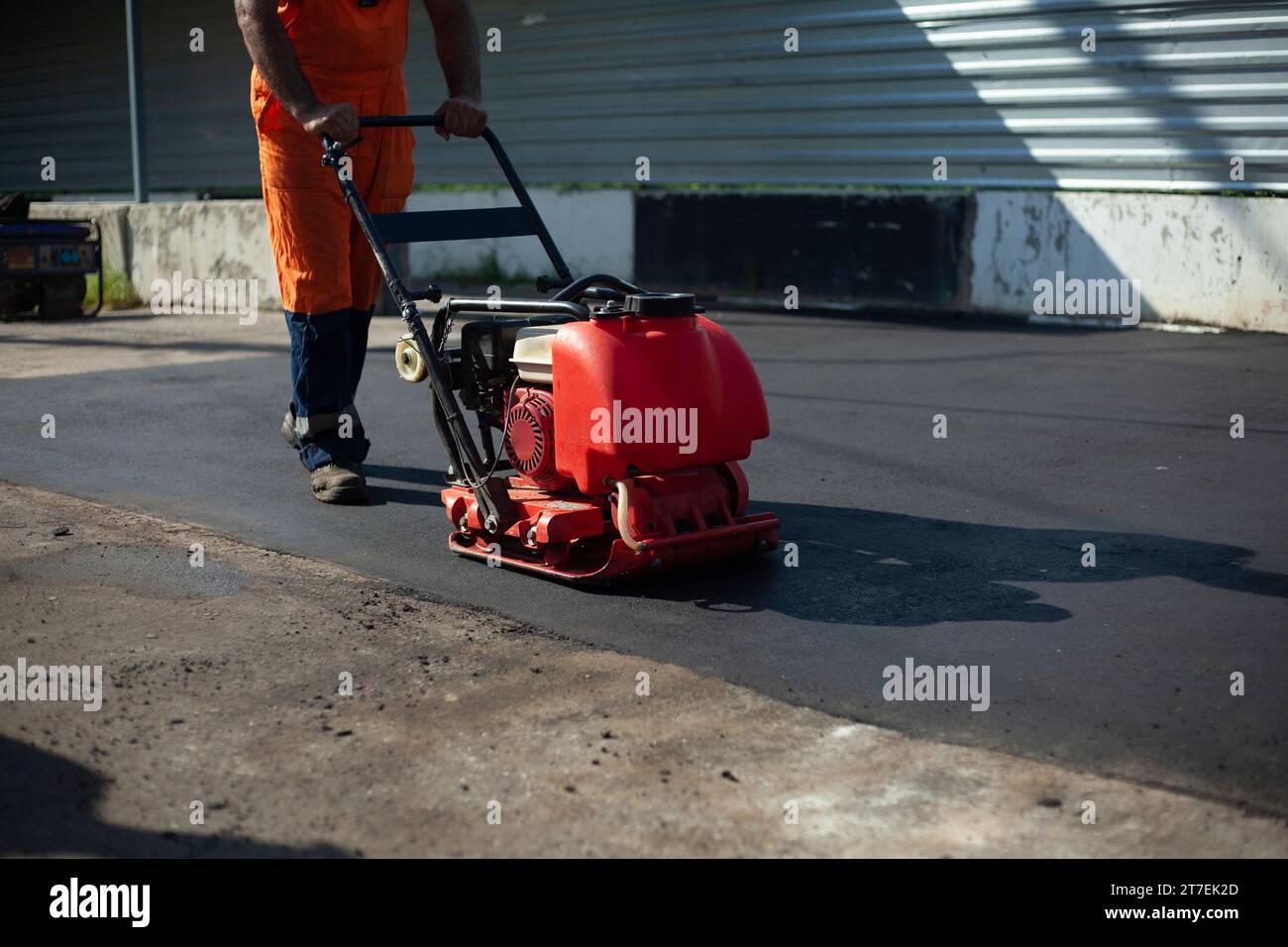 Macchina per pavimentazione asfalto. Il lavoratore compatte la carreggiata. Riparazione di strade. Attrezzatura diesel. Foto Stock