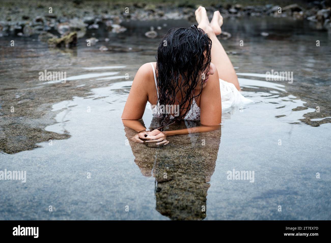 Una donna bruna in costume bianco si sta godendo un momento di relax approfittando delle terapie con acqua di mare Foto Stock