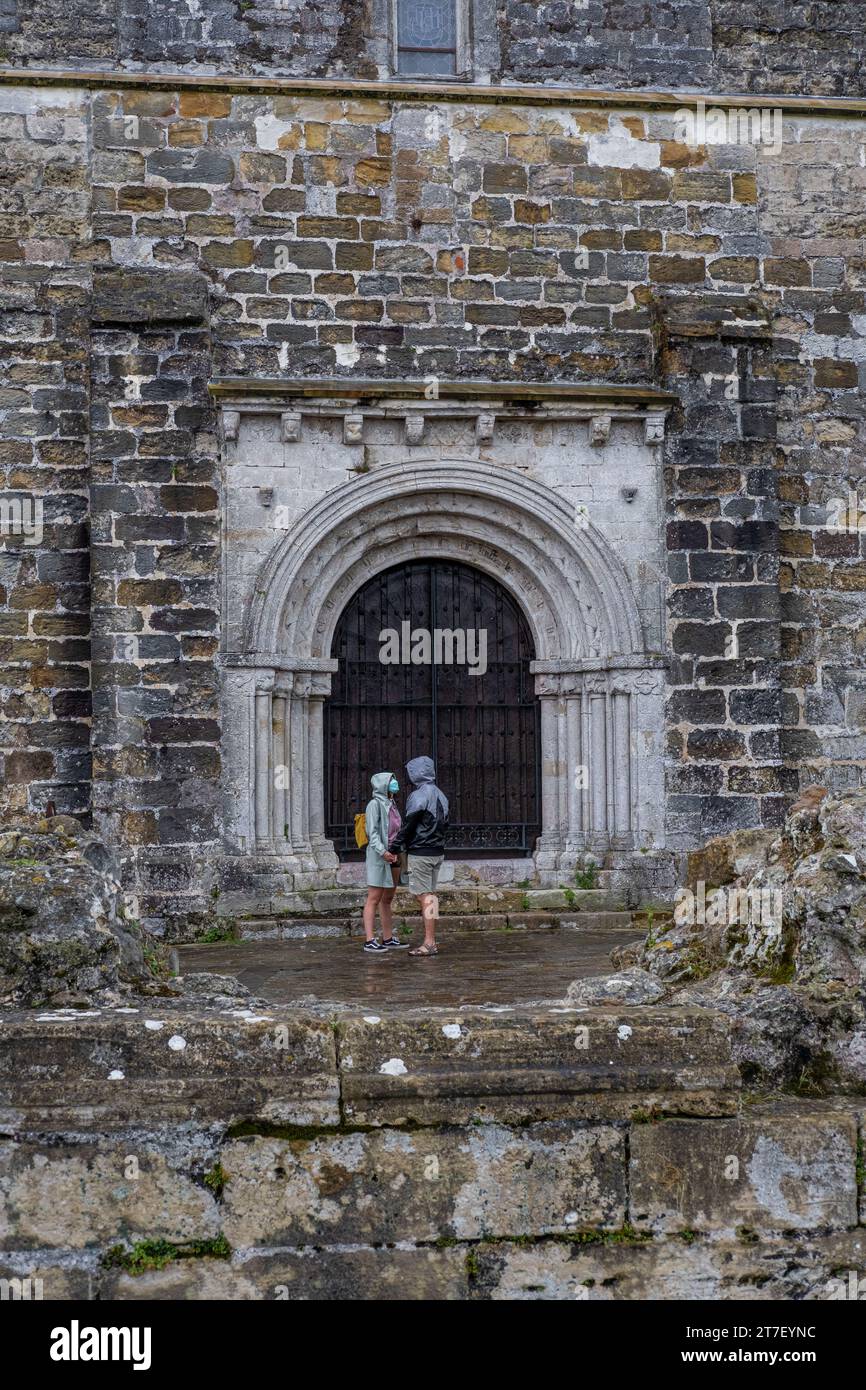 Un paio di viaggiatori sono molto affezionati alla porta di una vecchia chiesa in Cantabria, nel nord della Spagna. Foto Stock