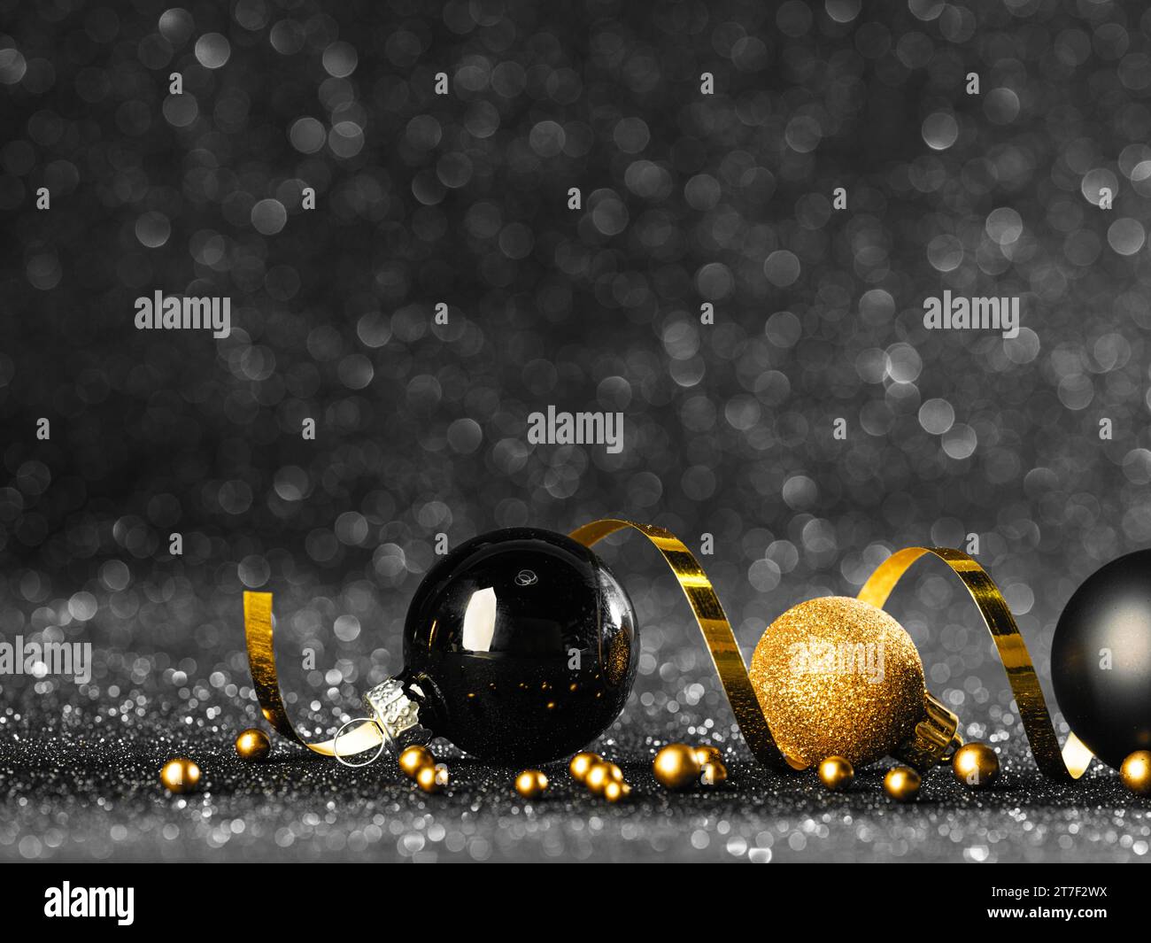 palline natalizie dorate e nere su sfondo bokeh nero Foto Stock