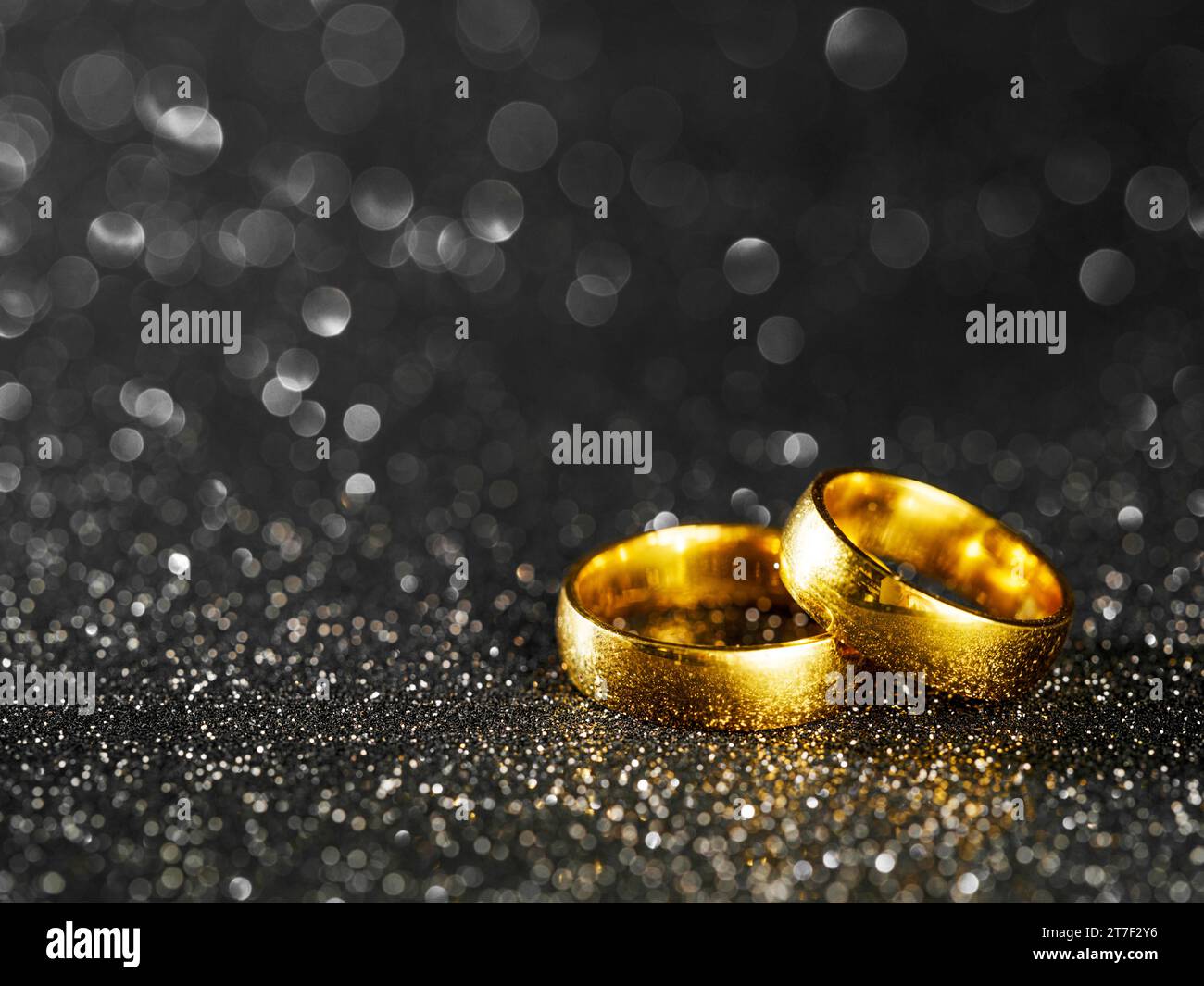 anelli dorati su sfondo nero bokeh Foto Stock