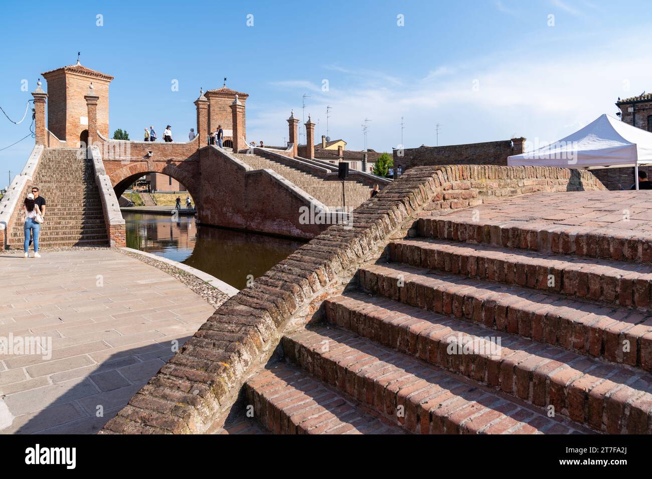 Comacchio, Italia-2 giugno 2023: Le persone passeggiano a Comacchio davanti ai famosi tre ponti durante una giornata di sole Foto Stock