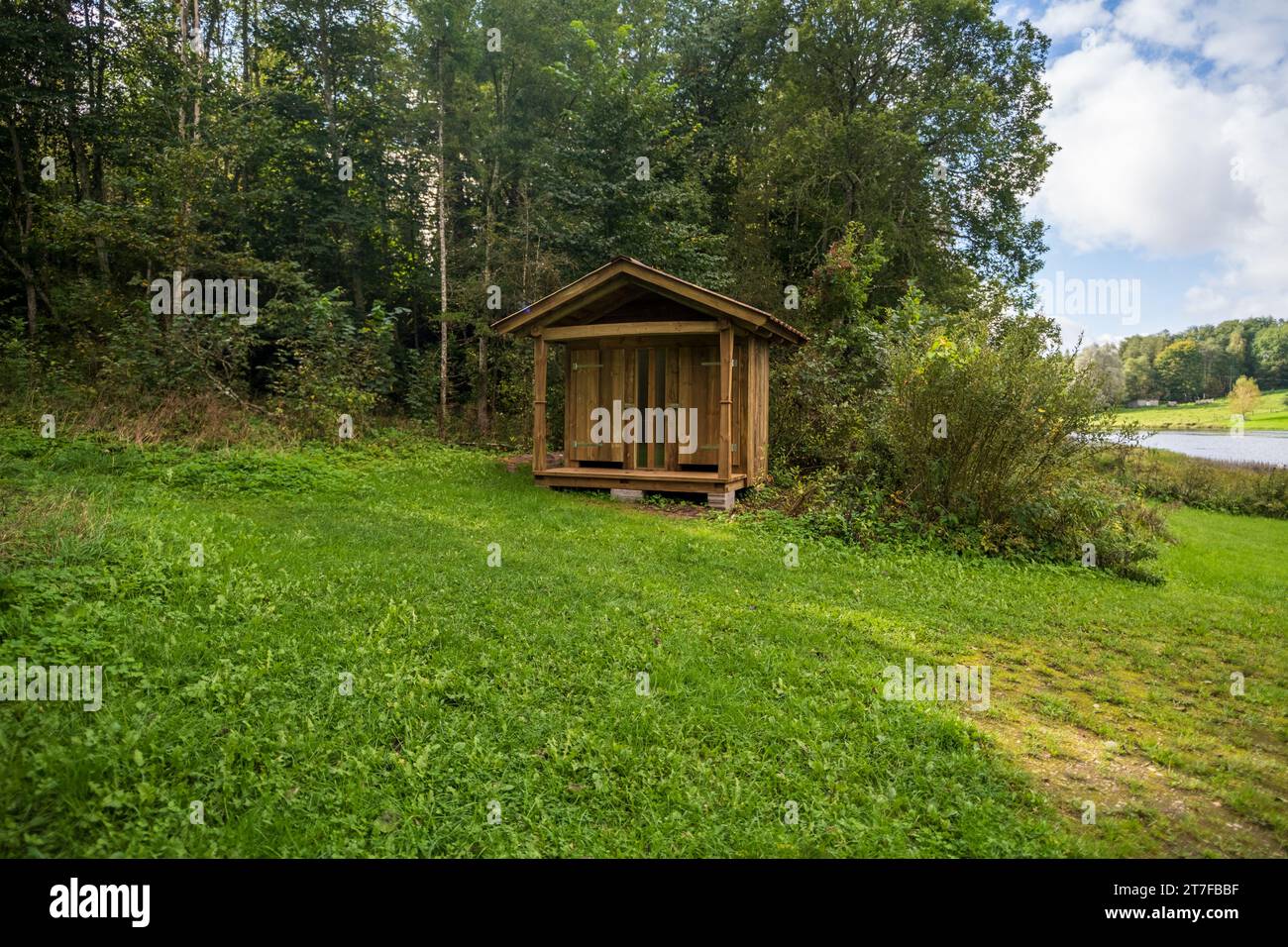 WC in legno in campagna con un foro a forma di cuore sulla porta. Bagno in legno su uno sfondo di alberi Foto Stock