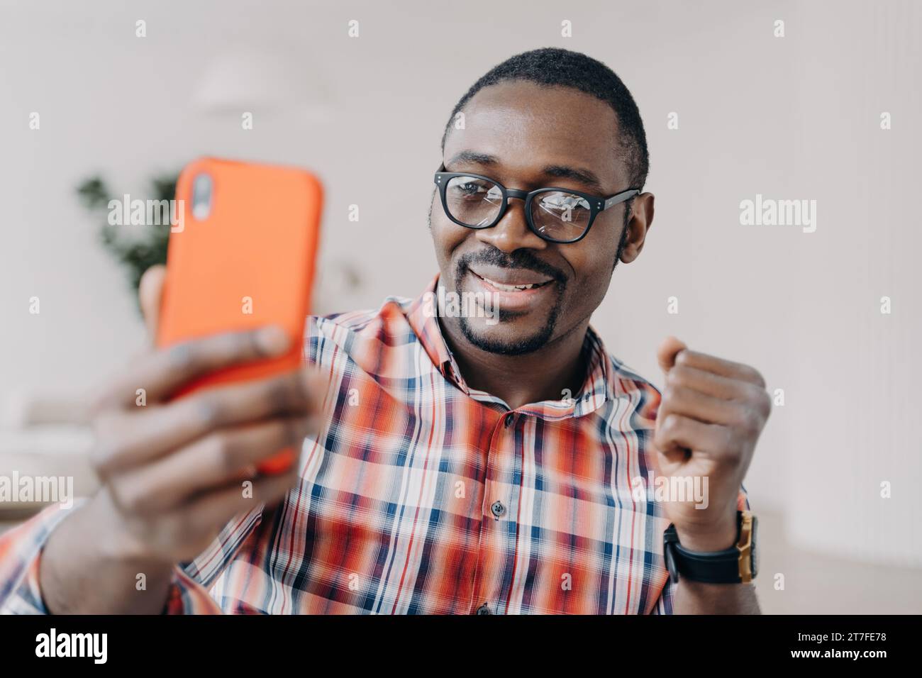 L'uomo con gli occhiali condivide con entusiasmo i contenuti sul suo smartphone, celebrando il successo Foto Stock