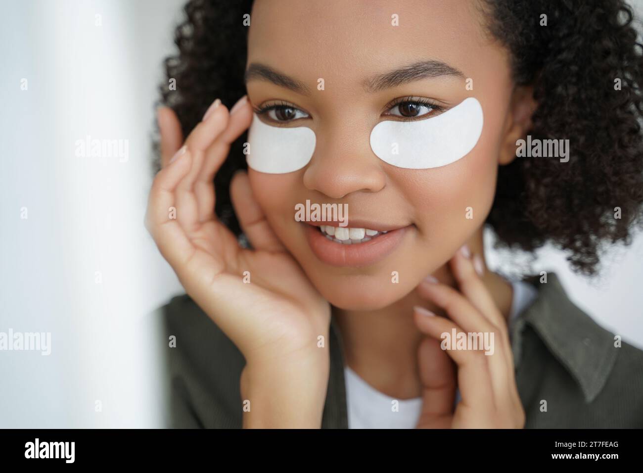 Donna nera con cerotti per il trattamento sotto gli occhi che si concentrano sulla bellezza della pelle Foto Stock