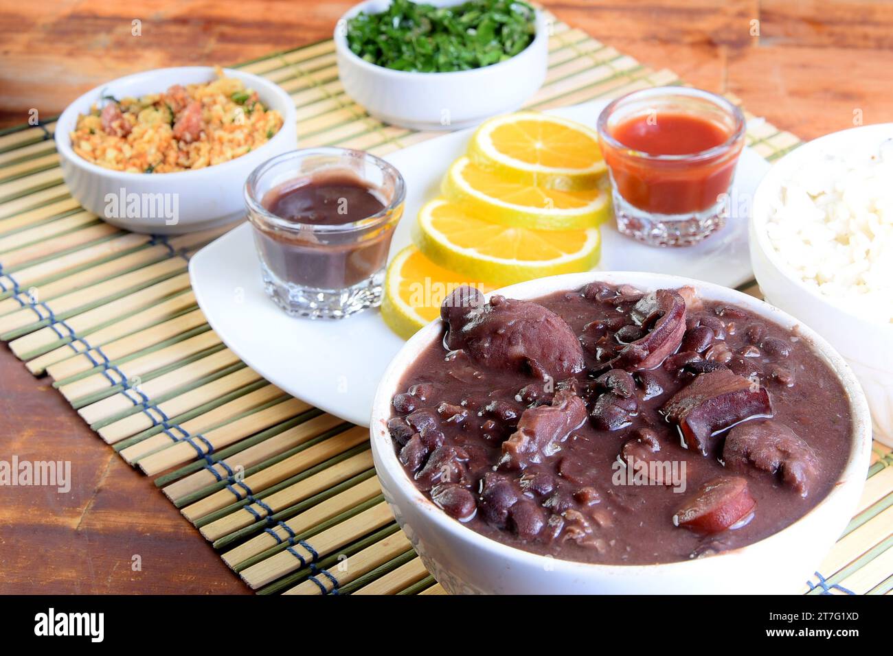 Delizioso cibo brasiliano feijoada con fagioli, maiale, pancetta, salsiccia con cavolo, riso, insalata, spezie e pepe. cucina rustica Foto Stock