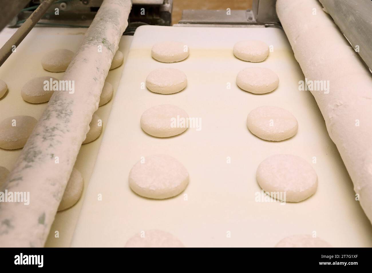 vista laterale delle torte precotte che attraversano i rulli della fabbrica la linea di produzione. Foto Stock