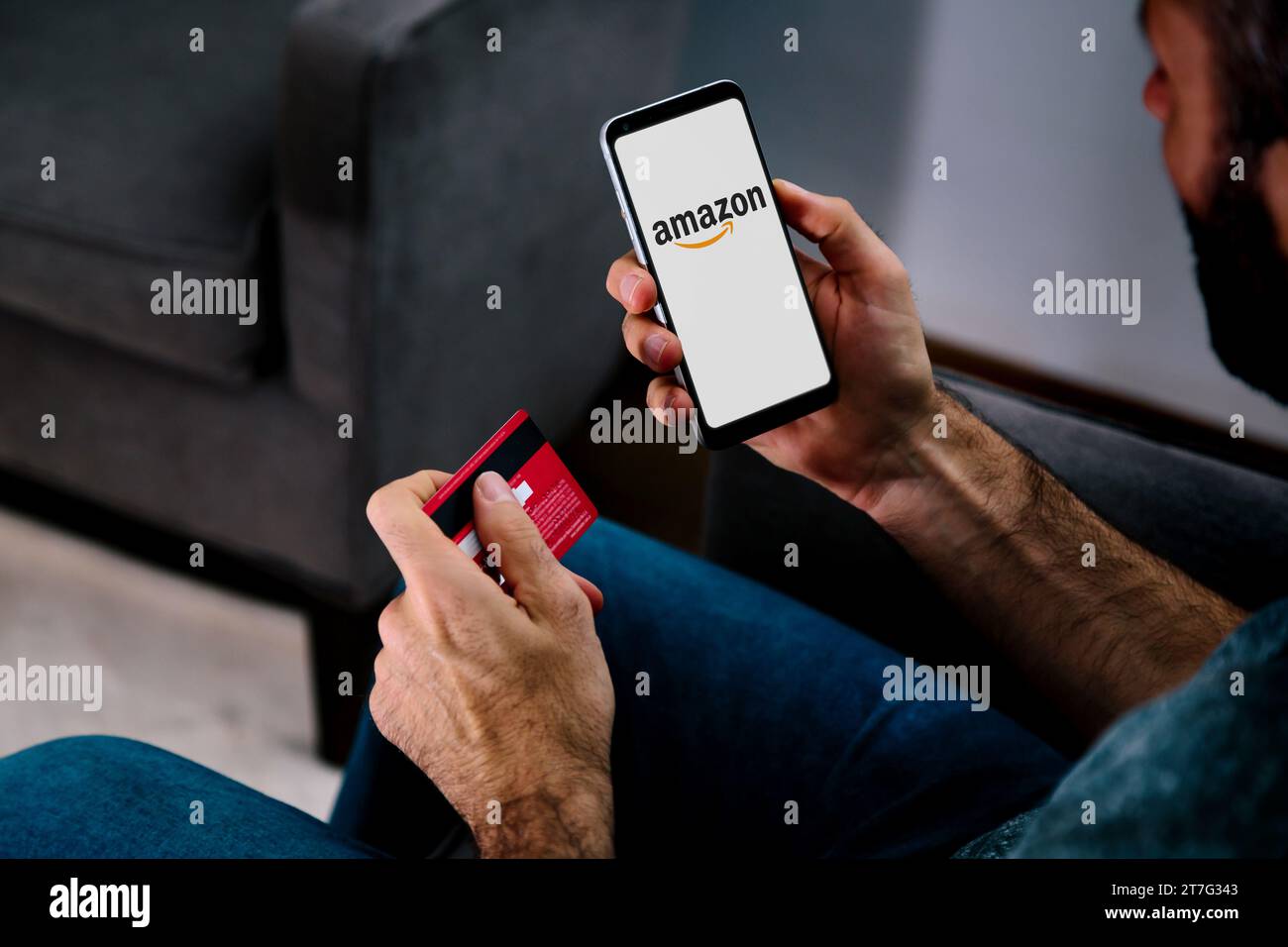 Logo Amazon sullo schermo del telefono tenuto da un uomo con una carta di credito. ROSARIO, ARGENTINA - 15 NOVEMBRE 2023. Foto Stock