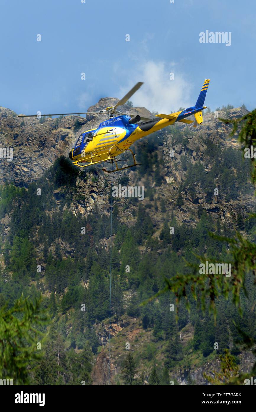 Valle d'Aosta 07-18-2022 Un elicottero cargo vola in un paesaggio montano Foto Stock