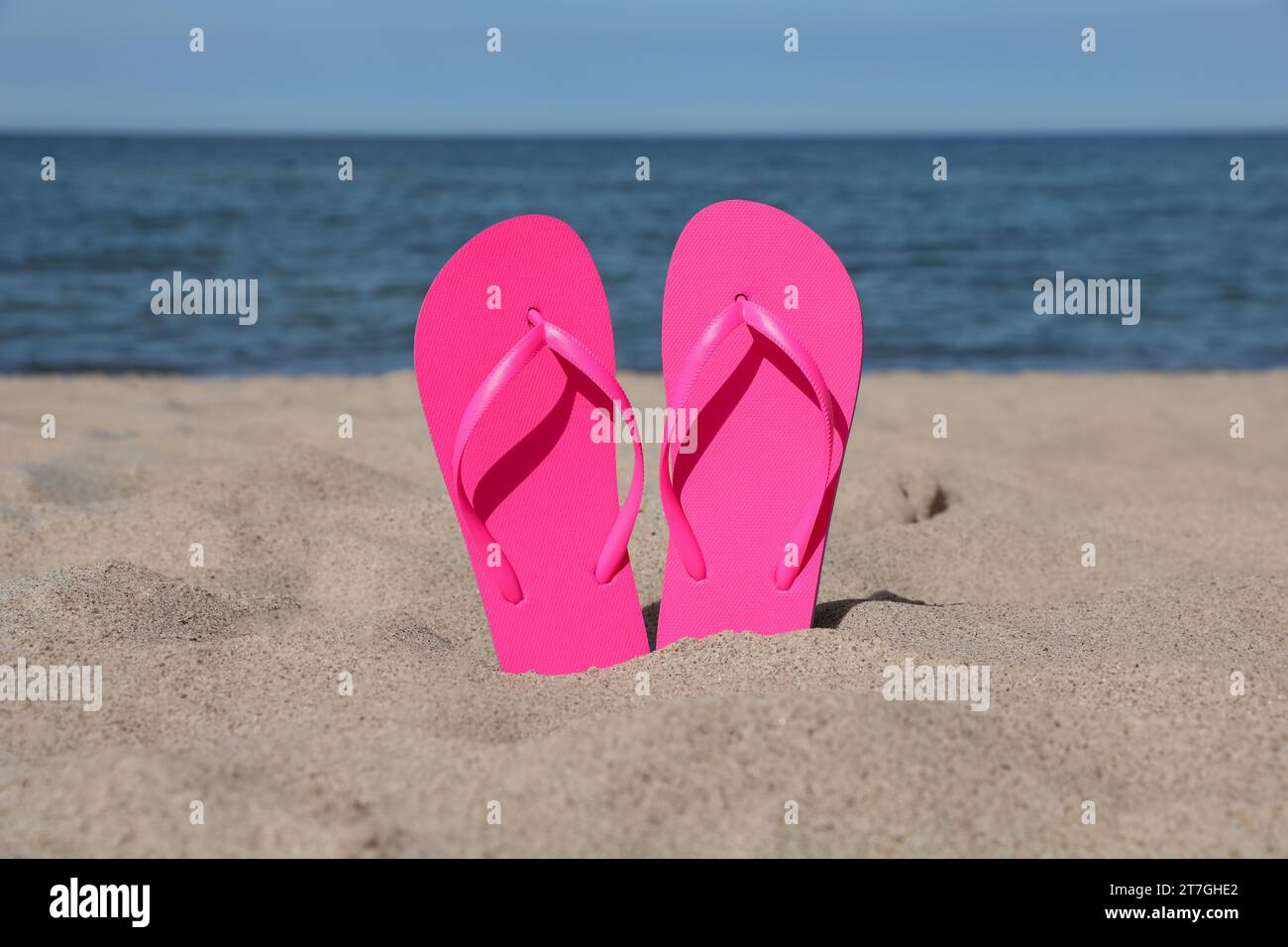 Eleganti infradito rosa sulla sabbia della spiaggia Foto Stock