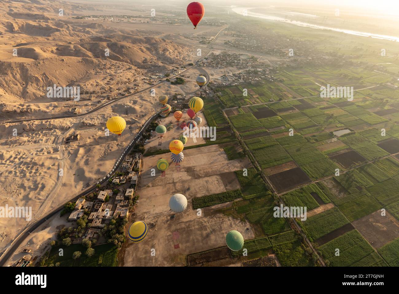 Vista aerea di un gruppo di mongolfiere che volano sul confine tra le sparse sabbie desertiche e i fertili campi agricoli della valle del Nilo Foto Stock