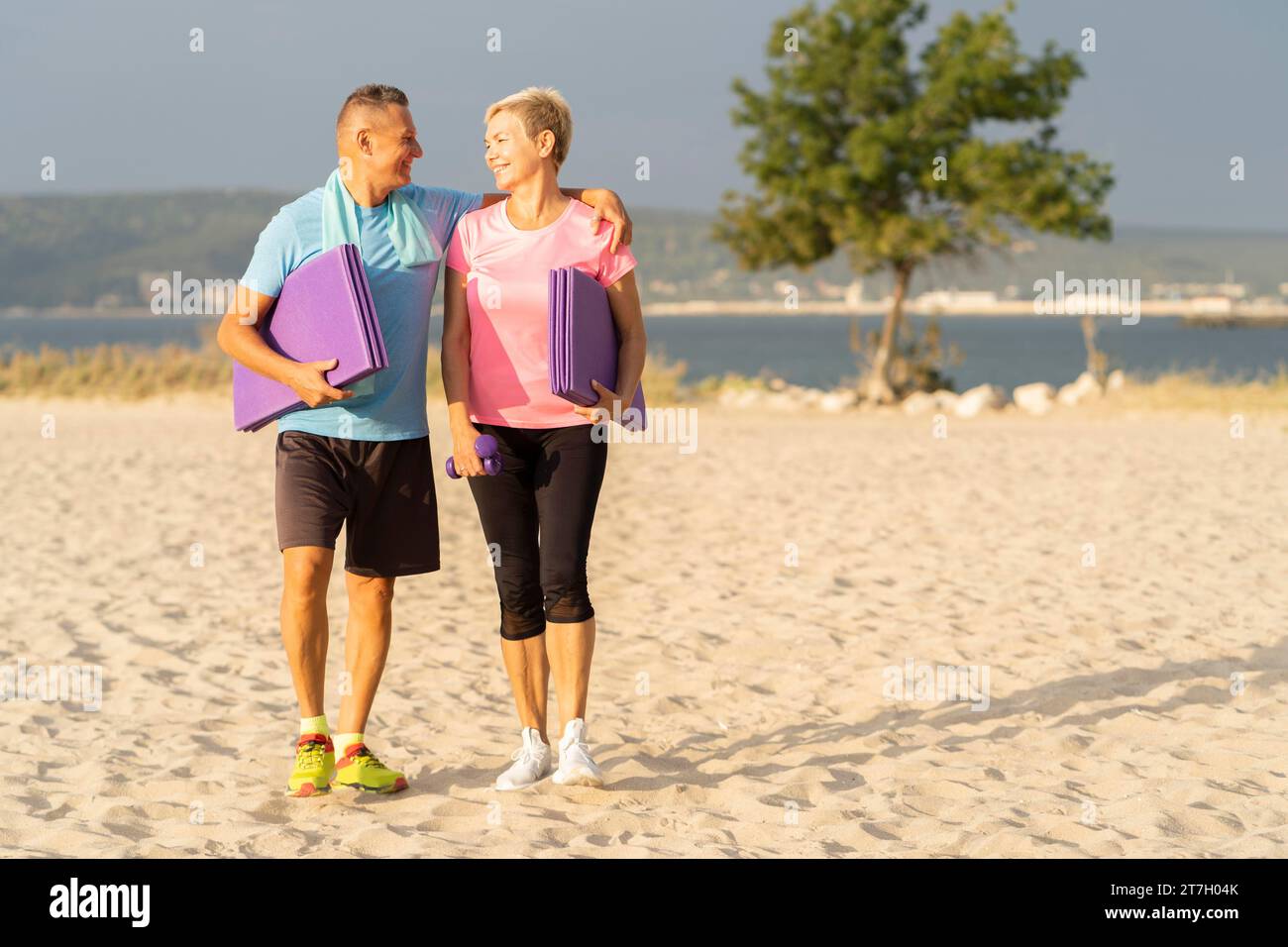 Coppia senior con attrezzature per l'allenamento, spazio fotocopie sulla spiaggia Foto Stock