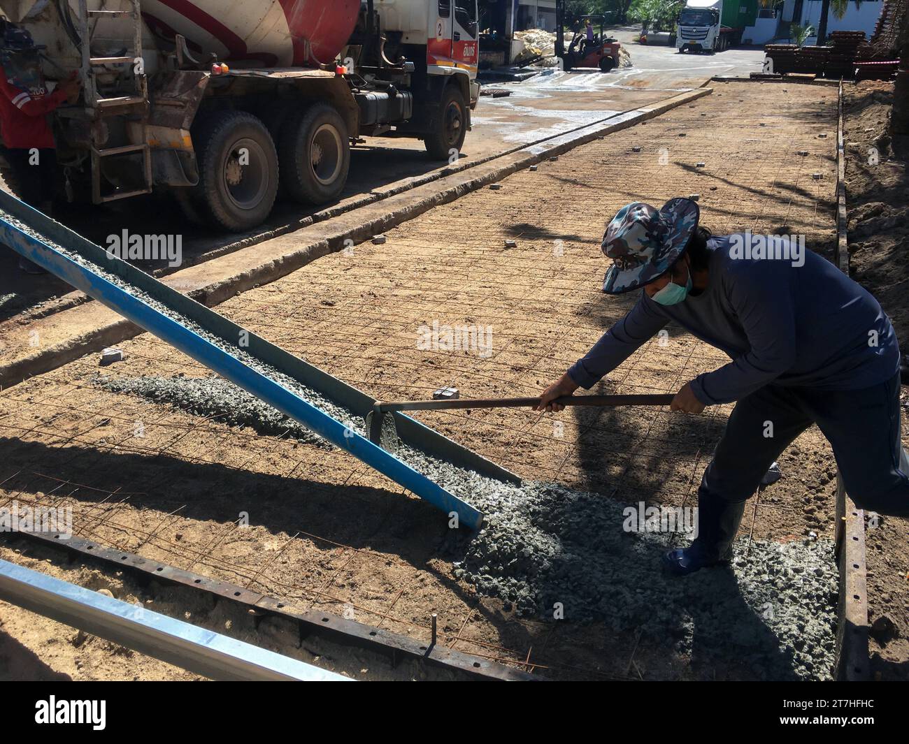 SURATTHANI, THAILANDIA - 12 maggio 2023 : i lavoratori scaricano cemento dai camion e lo diffondono in tutta la zona, questo è il processo di versamento del cemento Foto Stock
