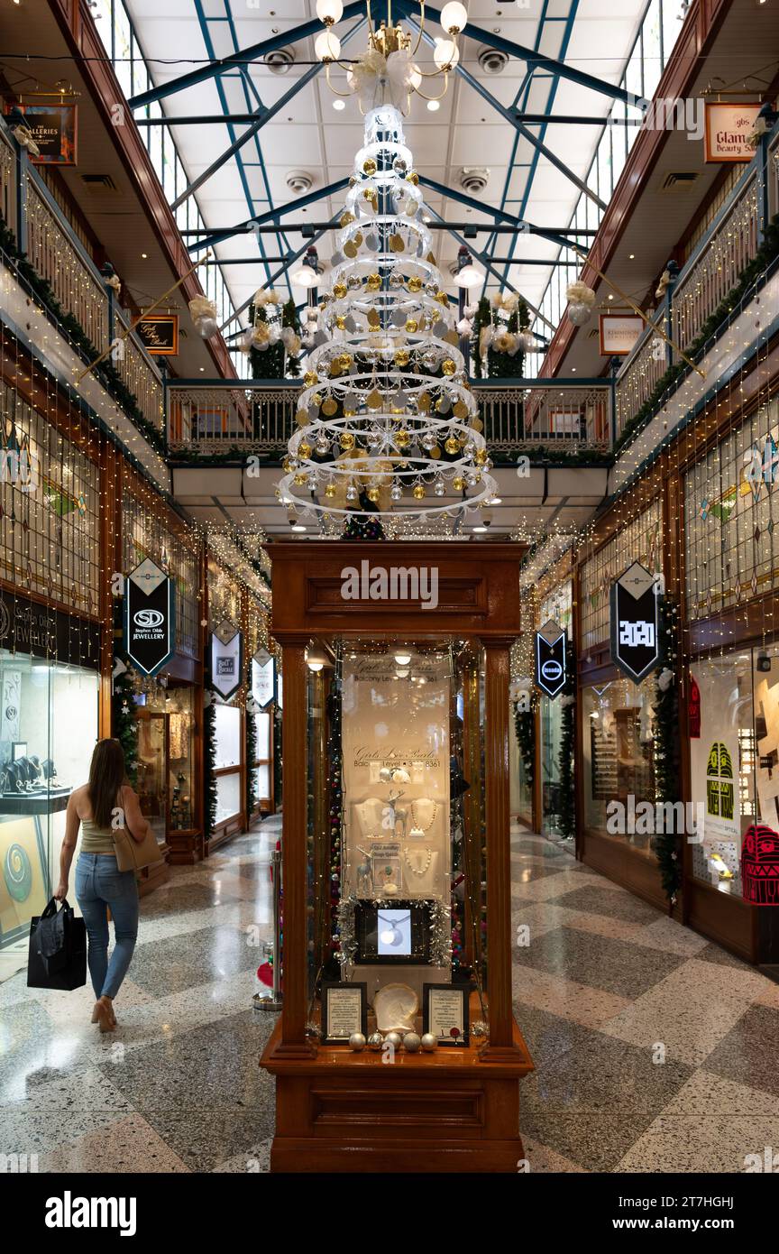 Un'unica donna che fa shopping natalizio cammina lungo Brisbane Arcade godendosi l'atmosfera di una delle gallerie dello shopping più iconiche della città di Brisbane. Foto Stock