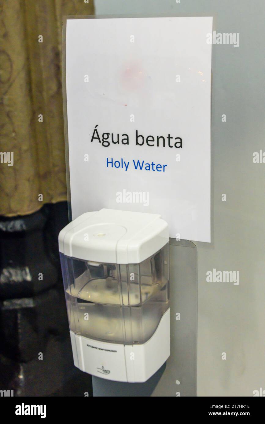 Dispenser di sapone riempito con acqua Santa all'ingresso di una chiesa cattolica portoghese. Foto Stock