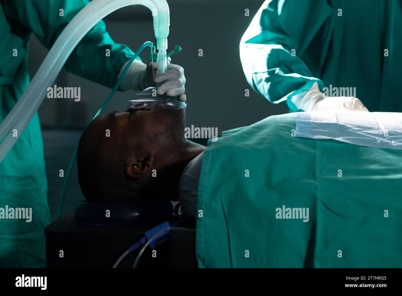 Diversi chirurghi che indossano camici chirurgici utilizzando maschera anestetica in sala operatoria in ospedale Foto Stock