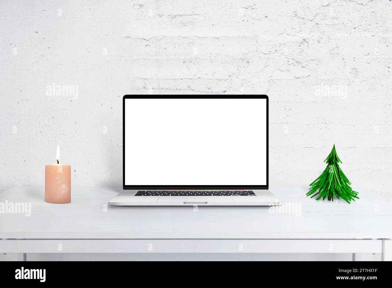 Mockup di un computer portatile sulla scrivania con decorazioni natalizie, albero e calendario. Ambiente accogliente per gli uffici delle festività per i saluti di stagione e la produttività. Foto Stock
