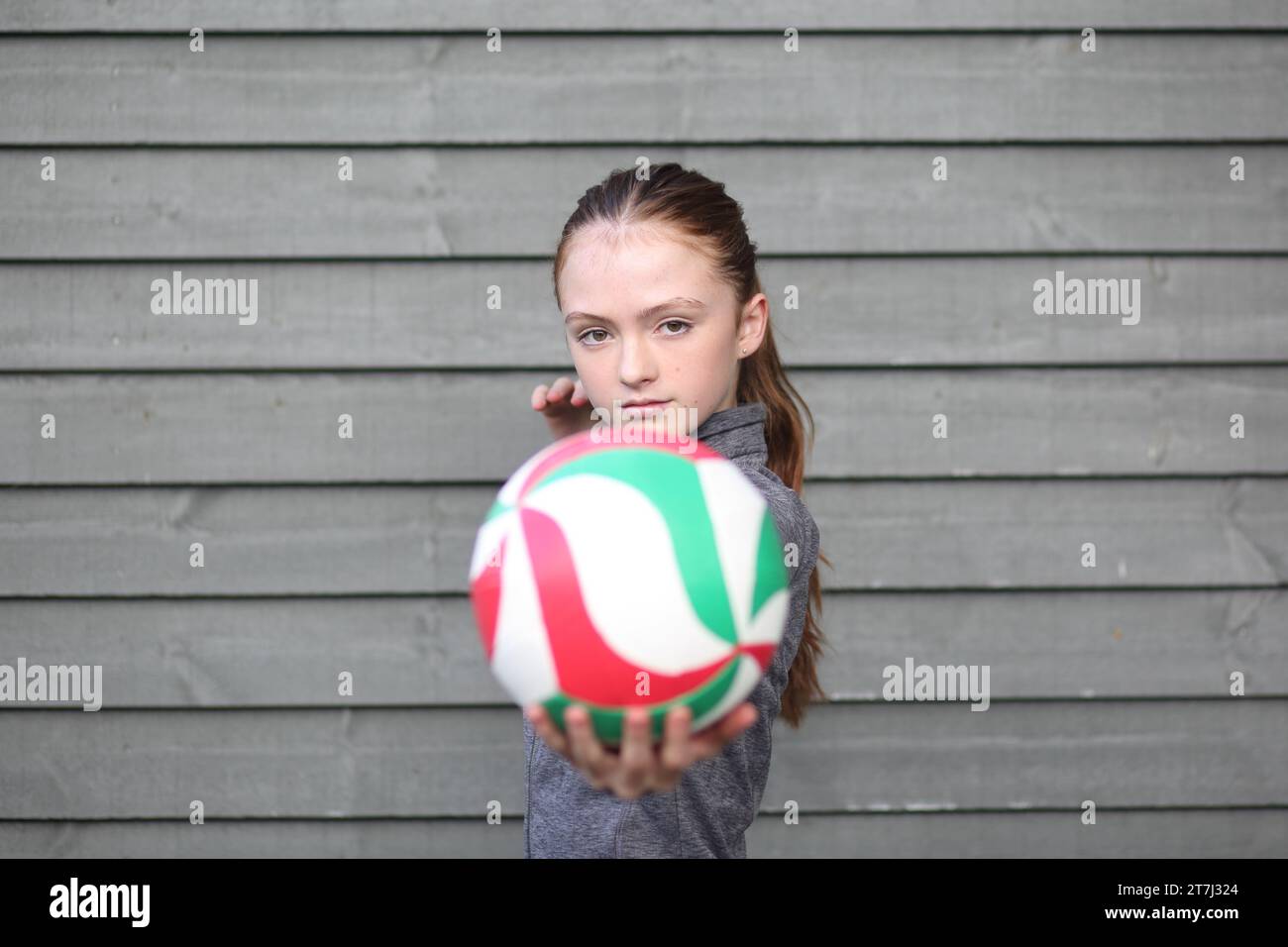 La ragazza adolescente tiene la pallavolo con la mano pronta a servire, fissando il copyspace della telecamera Foto Stock
