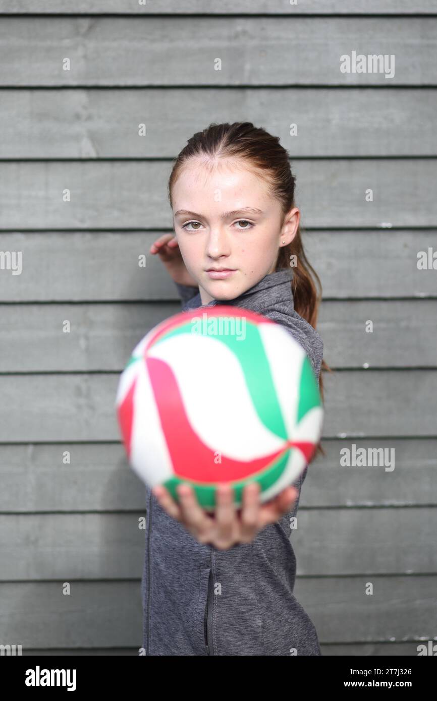 Adolescente che tiene la pallavolo nella mano sinistra pronta a servire con un contatto visivo diretto Foto Stock