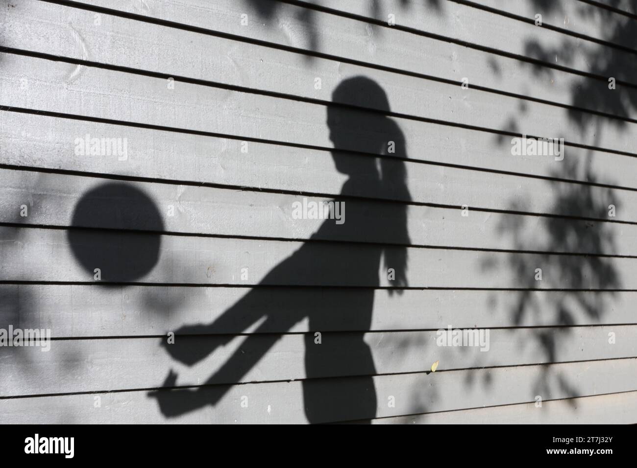 La ragazza adolescente pratica pallavolo tira l'ombra con la palla a mezz'aria con le braccia allungate Foto Stock