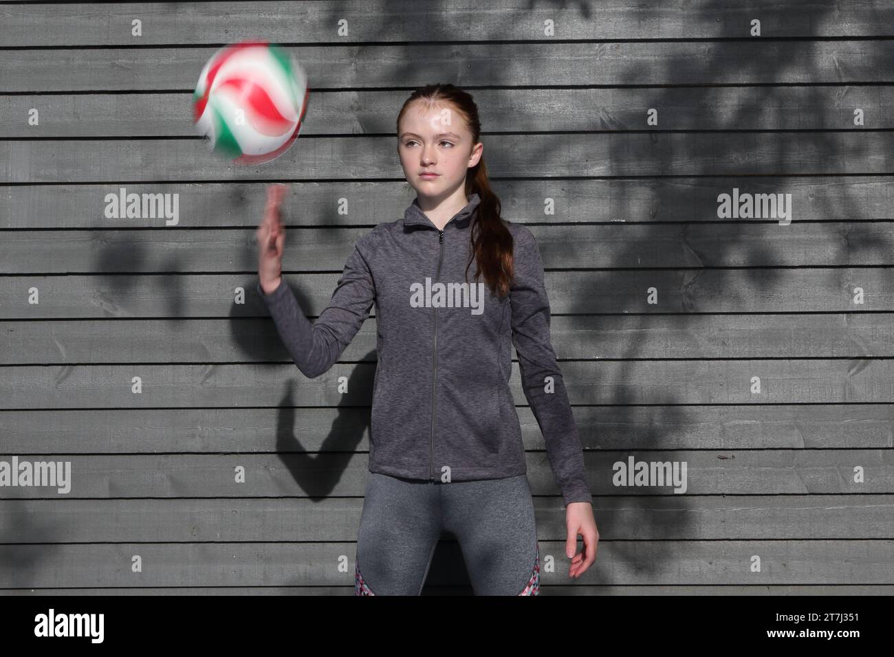 La ragazza adolescente pratica i tiri di pallavolo e lancia la palla in aria con palline sfocate e sfocate a mano Foto Stock