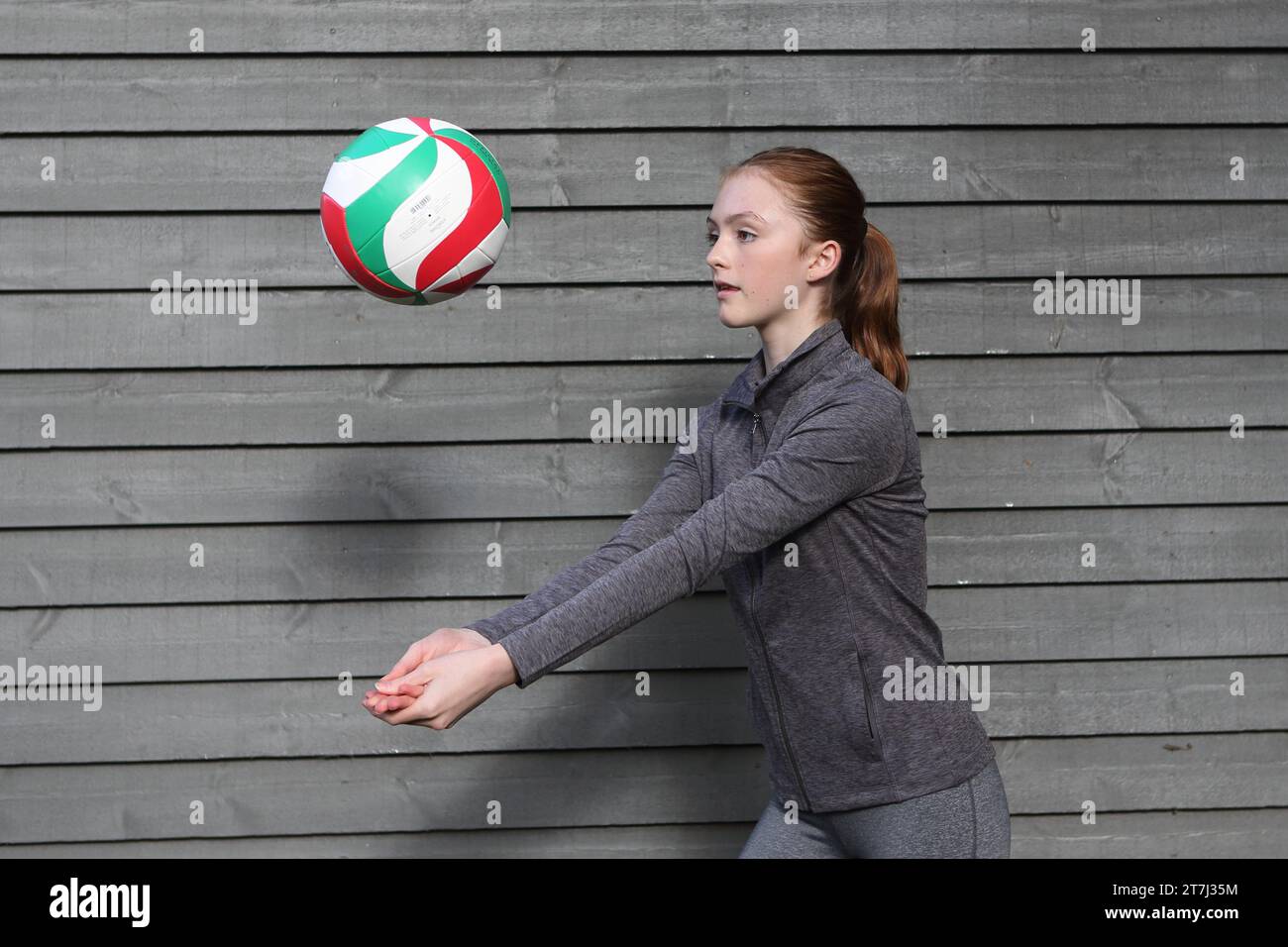 La ragazza adolescente pratica il tiro a pallavolo di fronte a uno sfondo semplice Foto Stock