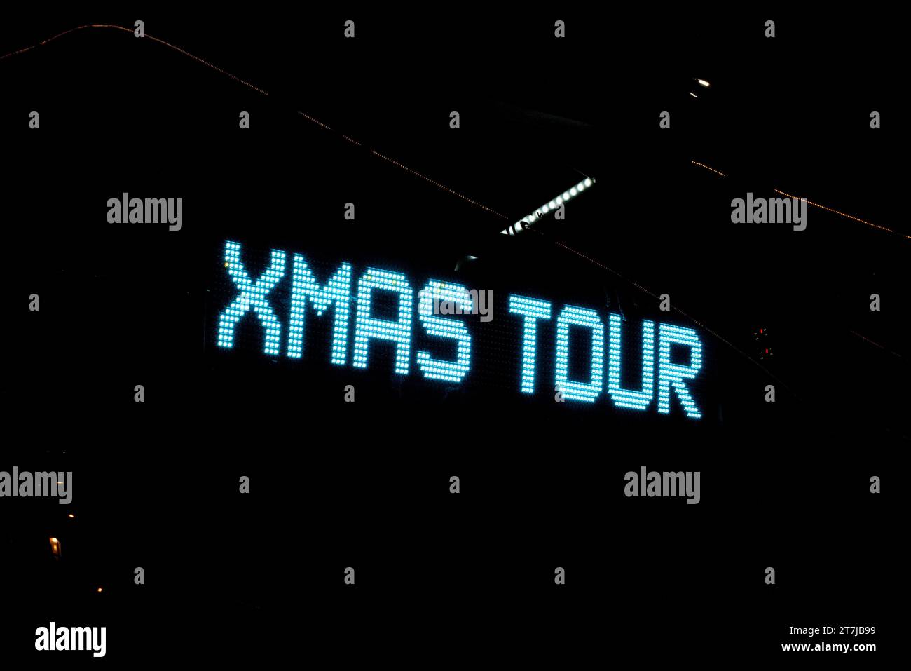 Incantevole tour natalizio: Un cartello blu luminoso brilla di notte, invitandovi in un magico viaggio di vacanza sotto il cielo stellato. Foto Stock