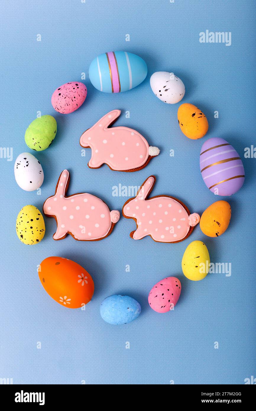 Tre pan di zenzero a forma di coniglio all'interno di una cornice ovale di uova di Pasqua multicolore Foto Stock