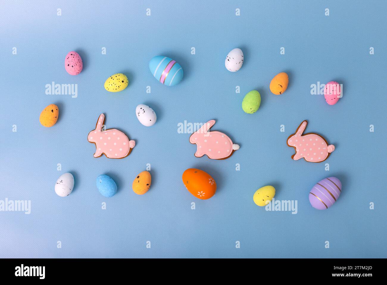 uova decorative multicolori e pan di zenzero rosa sotto forma di coniglio su sfondo blu Foto Stock