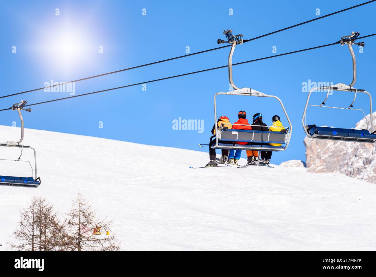 Sciatori in tute colorate che cavalcano una seggiovia in una località sciistica in una soleggiata giornata invernale Foto Stock