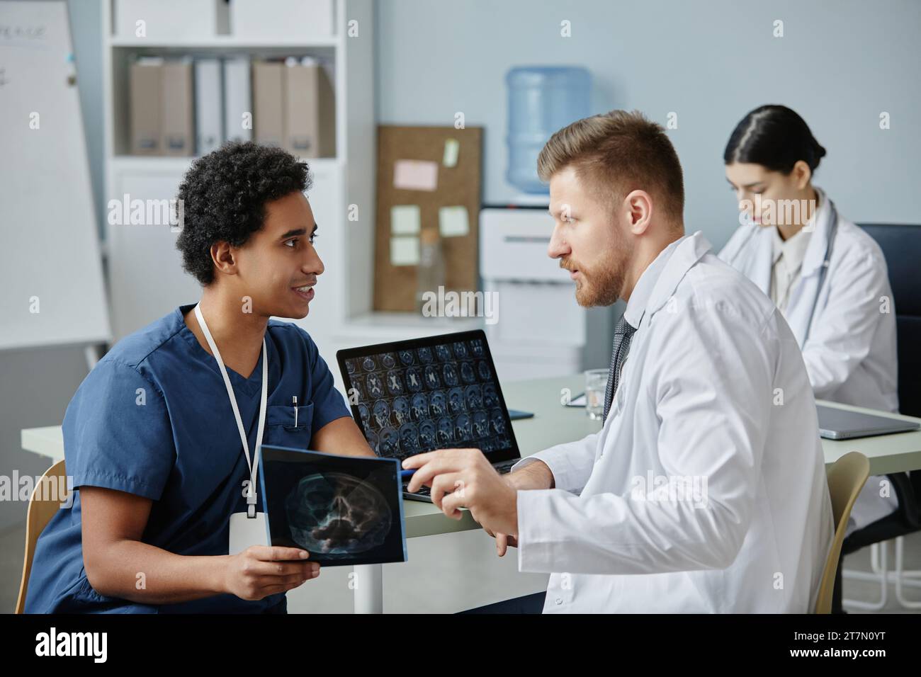 Vista laterale ritratto di due medici maschi che discutono di immagini radiografiche durante il lavoro in una clinica di radiologia Foto Stock