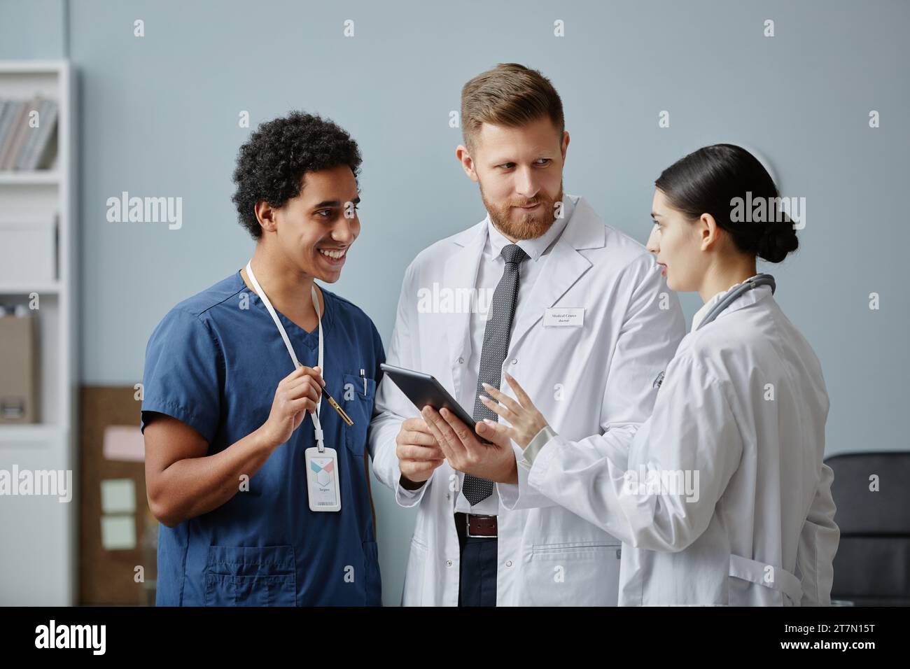 Ritratto in vita di tre medici che discutono del caso di un paziente in clinica e in una tavoletta Foto Stock